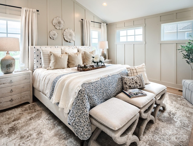 bedroom featuring dark hardwood / wood-style flooring, vaulted ceiling, and multiple windows