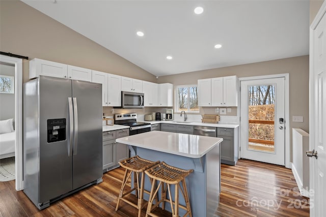 kitchen featuring appliances with stainless steel finishes, sink, gray cabinetry, a kitchen breakfast bar, and a center island