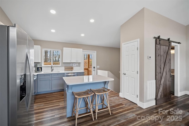 kitchen featuring sink, appliances with stainless steel finishes, white cabinetry, a center island, and a barn door