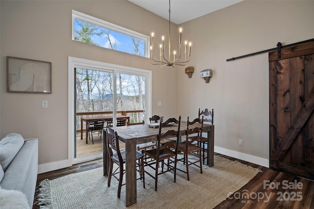 dining area with hardwood / wood-style flooring, a barn door, and a notable chandelier