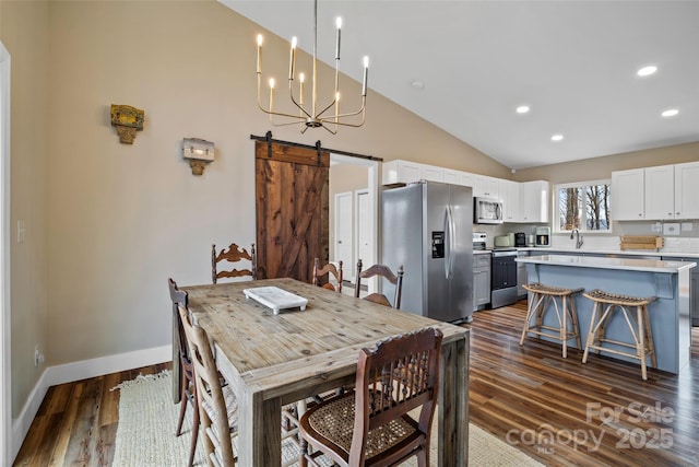 dining room featuring lofted ceiling, sink, a notable chandelier, dark hardwood / wood-style flooring, and a barn door