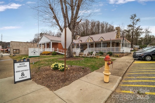 186 S Slope Ln, Old Fort, NC 28762 - view of front facade featuring a chimney, a porch, metal roof, and concrete driveway