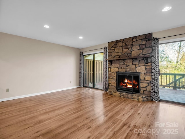 unfurnished living room featuring a stone fireplace and light hardwood / wood-style flooring