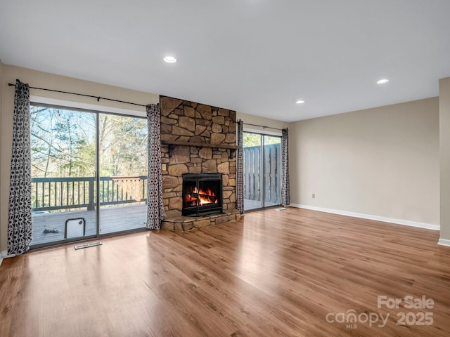 unfurnished living room with a stone fireplace and hardwood / wood-style floors