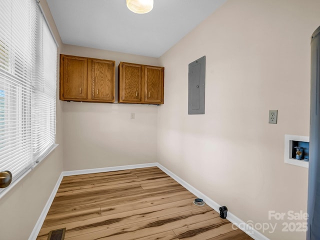 clothes washing area featuring cabinets, washer hookup, electric panel, and light wood-type flooring