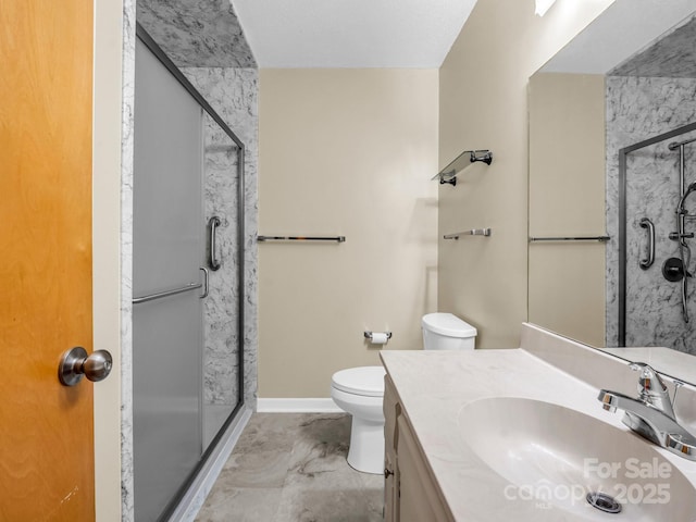 bathroom featuring a shower with door, vanity, and toilet