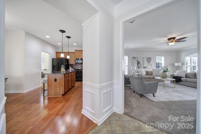 kitchen with decorative light fixtures, washer / dryer, a kitchen bar, a center island, and black appliances