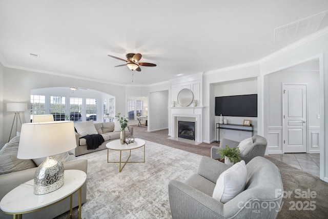 living room with ceiling fan, ornamental molding, and light carpet