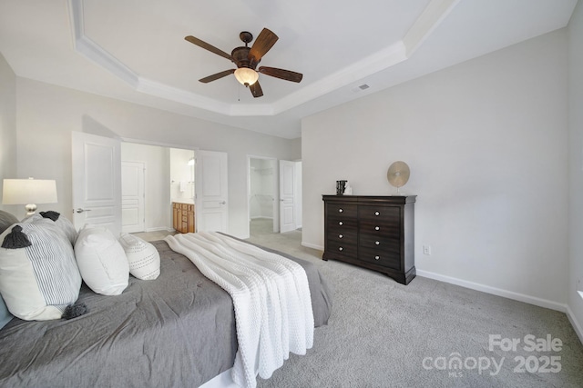 carpeted bedroom with ensuite bath, a raised ceiling, and ceiling fan