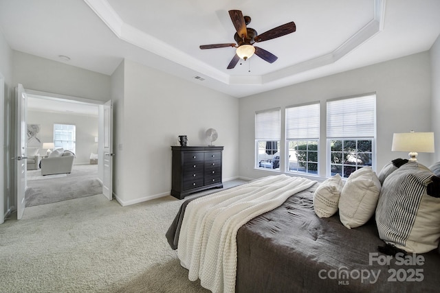 bedroom featuring a raised ceiling, light carpet, and ceiling fan