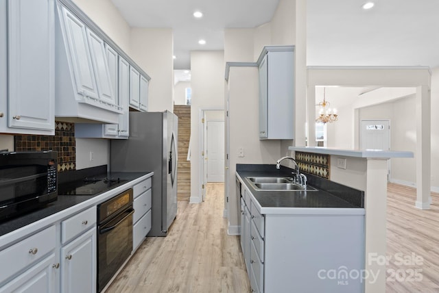 kitchen with gray cabinetry, light hardwood / wood-style floors, sink, and black appliances