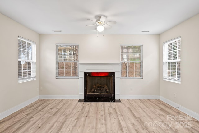 unfurnished living room with ceiling fan, a wealth of natural light, and light wood-type flooring