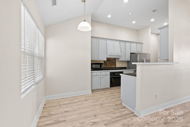 kitchen with vaulted ceiling, black appliances, hanging light fixtures, kitchen peninsula, and light wood-type flooring