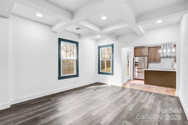 unfurnished living room featuring baseboards, coffered ceiling, wood finished floors, and beamed ceiling