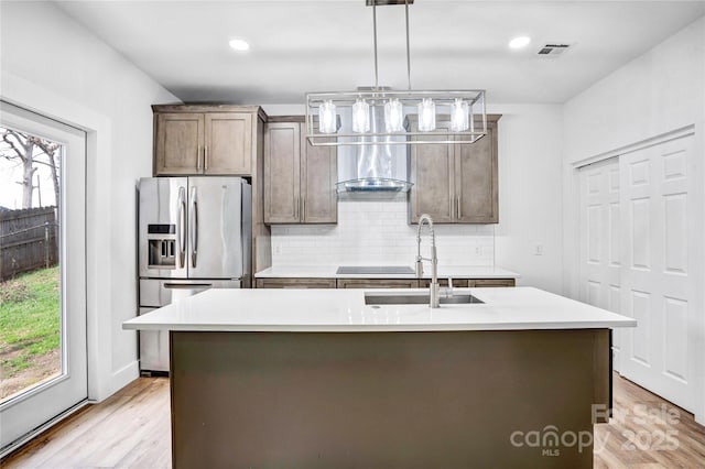 kitchen with light countertops, tasteful backsplash, stainless steel fridge, and a sink