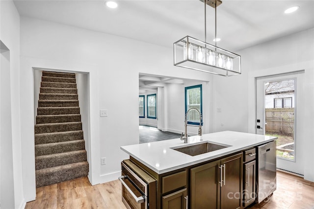 kitchen featuring light wood finished floors, recessed lighting, light countertops, stainless steel dishwasher, and a sink