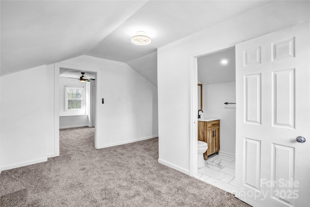 bonus room with lofted ceiling, marble finish floor, a sink, and baseboards