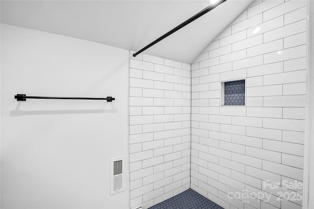 full bathroom featuring a tile shower, visible vents, and vaulted ceiling