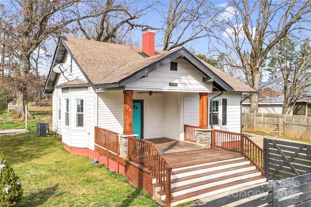 bungalow with a chimney, central AC, fence, ceiling fan, and a front lawn