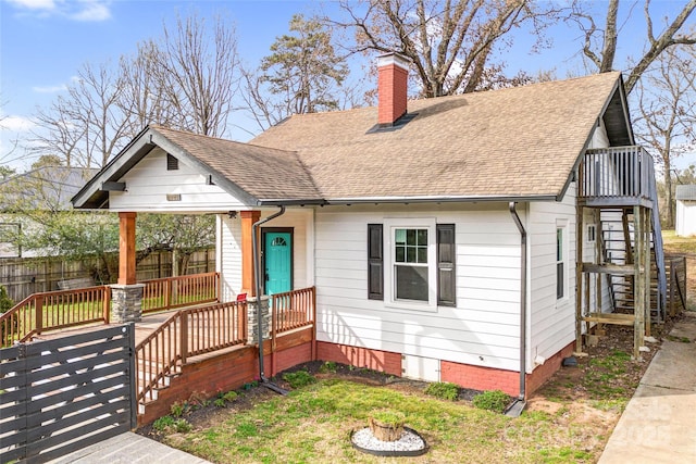 bungalow featuring a shingled roof, fence, a chimney, and stairs