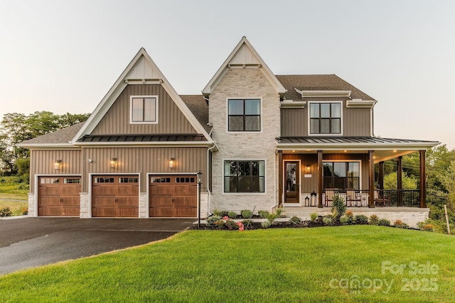 view of front of property with a porch, a garage, and a front lawn