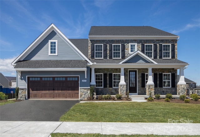 view of front facade featuring a garage, a front yard, and covered porch