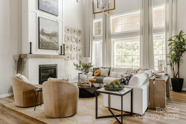 living area featuring a high ceiling, a brick fireplace, and light wood-type flooring