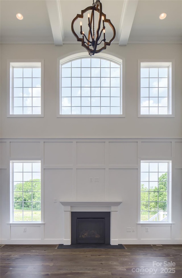 unfurnished living room featuring ornamental molding, dark hardwood / wood-style flooring, a notable chandelier, and beam ceiling