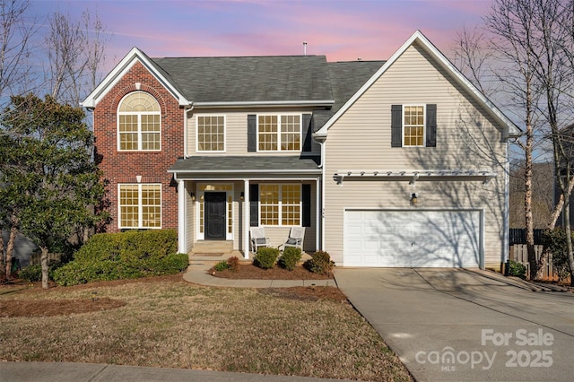 traditional-style house featuring an attached garage, a front lawn, concrete driveway, and brick siding