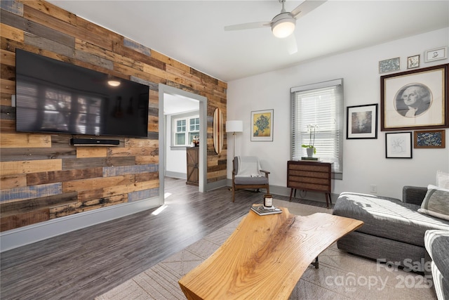 living room featuring hardwood / wood-style floors, wooden walls, and ceiling fan