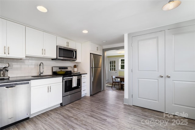 kitchen featuring sink, tasteful backsplash, appliances with stainless steel finishes, light hardwood / wood-style floors, and white cabinets