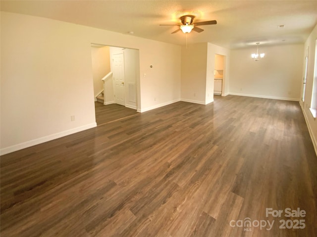 spare room with dark wood-type flooring and ceiling fan with notable chandelier