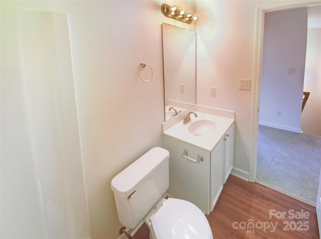 bathroom with hardwood / wood-style flooring, vanity, and toilet