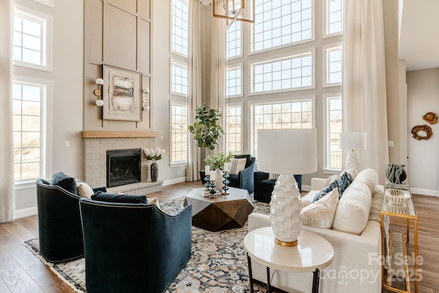 living room featuring a towering ceiling, a fireplace, and light hardwood / wood-style floors