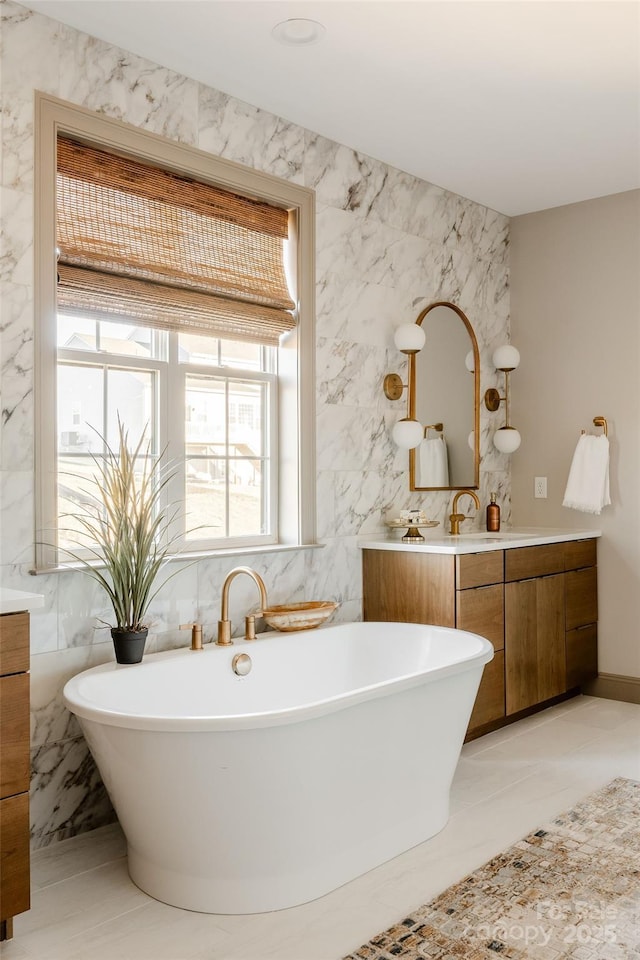 bathroom featuring a washtub, vanity, and tile walls