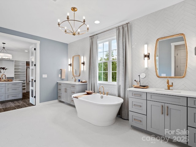 bathroom featuring vanity, tasteful backsplash, a bathing tub, and an inviting chandelier