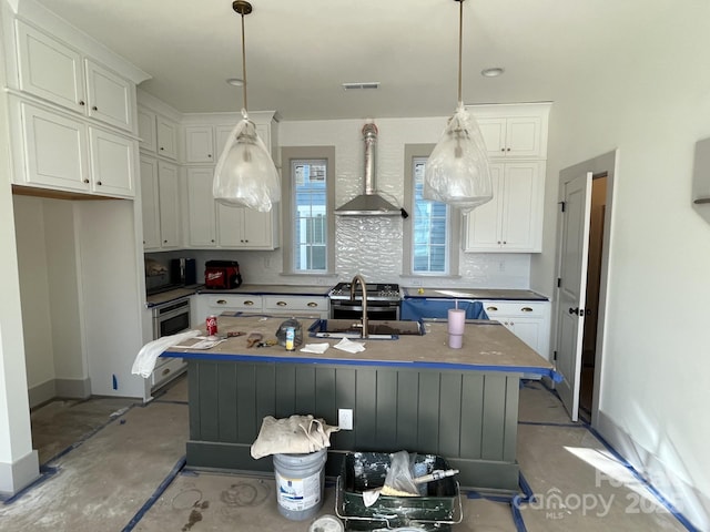 kitchen with wall chimney range hood, sink, white cabinets, and a center island with sink