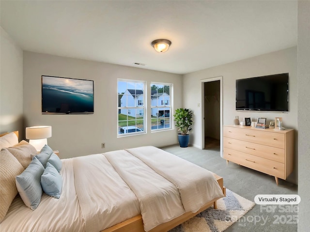 bedroom with a walk in closet and light colored carpet