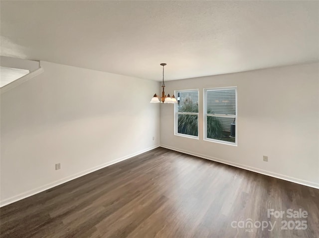 unfurnished room with dark wood-type flooring and a notable chandelier