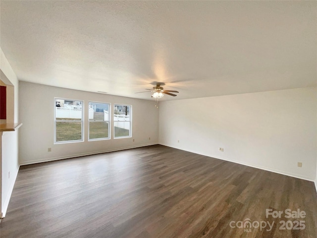 empty room with ceiling fan, dark hardwood / wood-style floors, and a textured ceiling