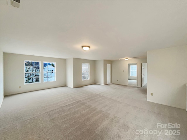 empty room featuring plenty of natural light and light colored carpet