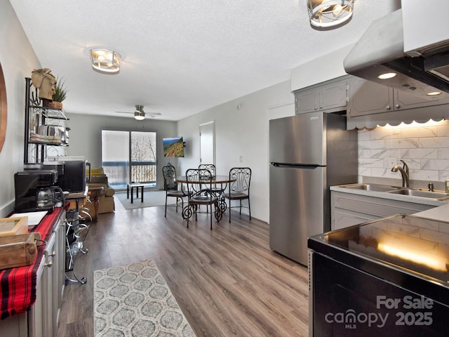 kitchen with gray cabinets, hardwood / wood-style flooring, sink, and stainless steel refrigerator