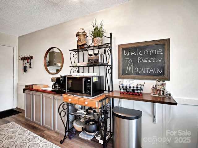 bar featuring wood counters, dark wood-type flooring, and a textured ceiling