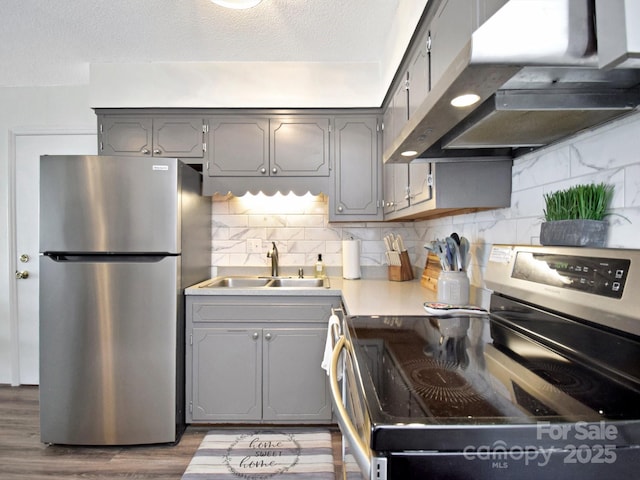 kitchen featuring appliances with stainless steel finishes, tasteful backsplash, sink, gray cabinetry, and light wood-type flooring