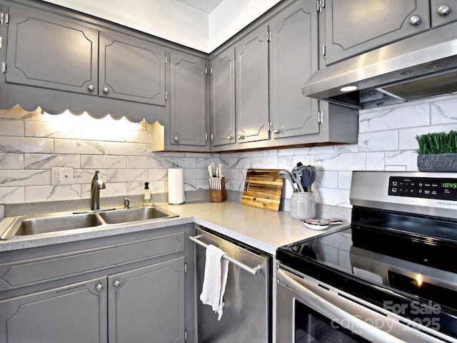 kitchen featuring tasteful backsplash, appliances with stainless steel finishes, sink, and gray cabinetry