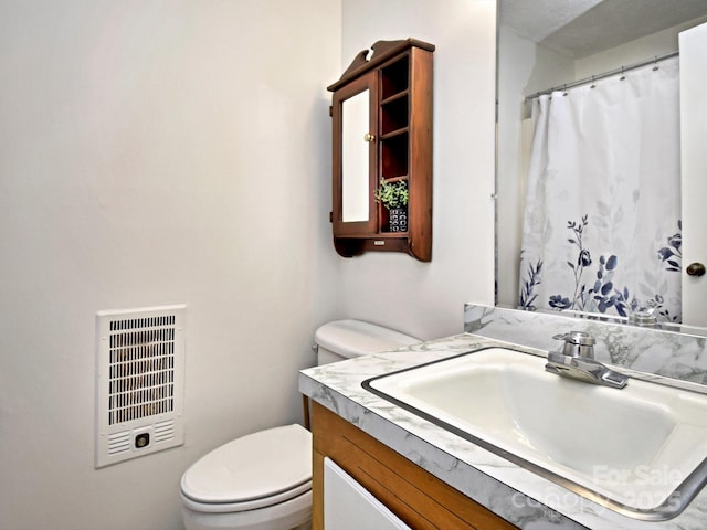 bathroom featuring vanity, heating unit, and toilet