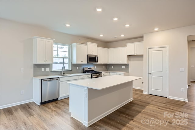 kitchen featuring sink, tasteful backsplash, a kitchen island, stainless steel appliances, and white cabinets