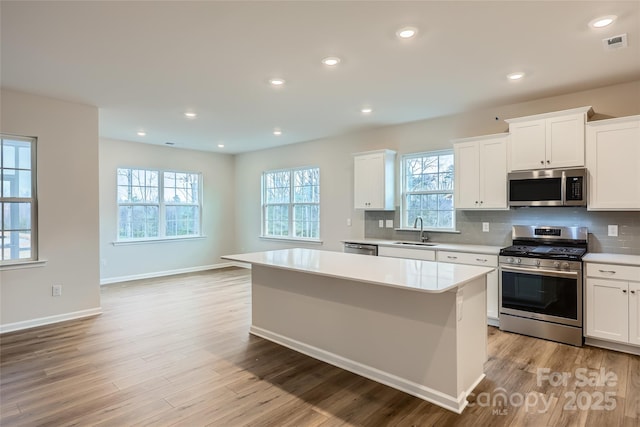 kitchen with appliances with stainless steel finishes, a center island, sink, and white cabinets