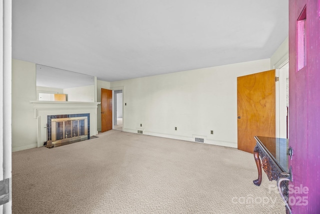 unfurnished living room featuring a tiled fireplace and light carpet