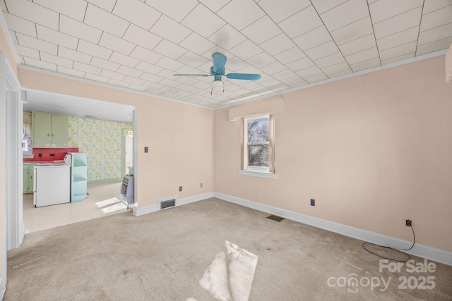 carpeted empty room featuring crown molding, washing machine and clothes dryer, and ceiling fan